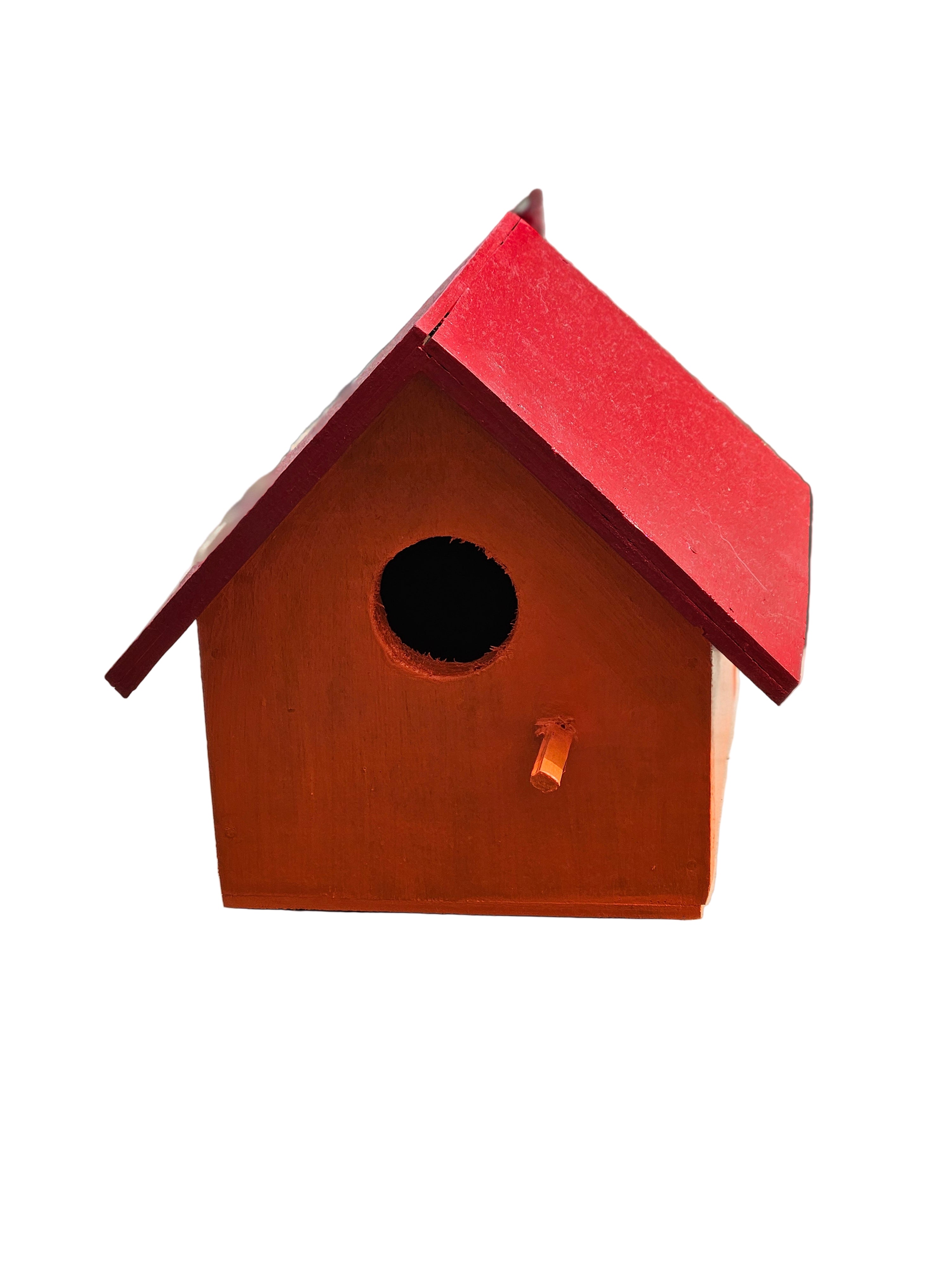 Red birdhouse attached to a concrete wall