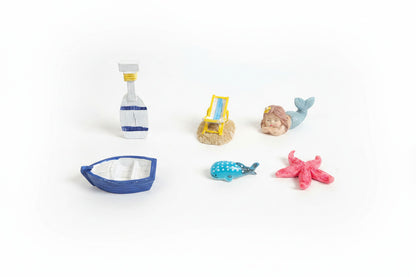 Colorful toy figurines of a bottle, beach chair, mermaid, boat, and starfish on a brown surface.