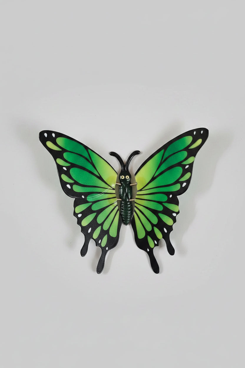Green butterfly decoration on a white sheet of paper with a colorful tablecloth in the background.